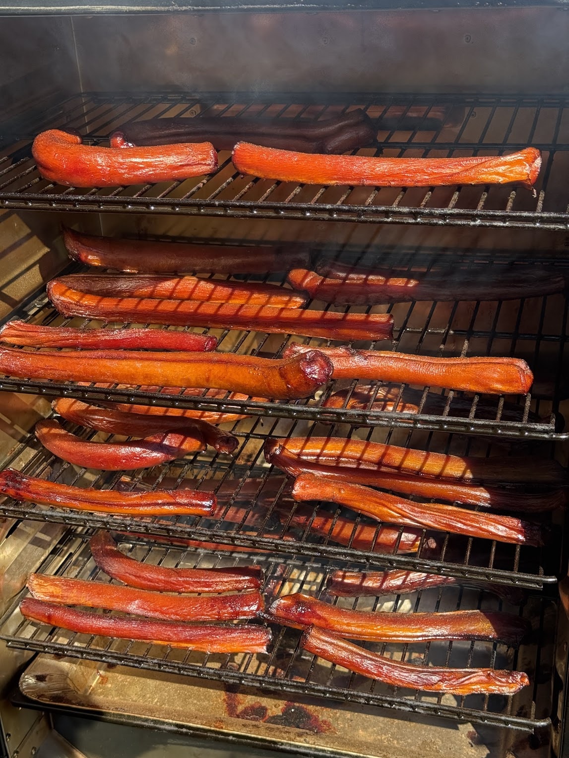 Homemade beef pizzles slow-smoking on racks in Honey's Small Kitchen